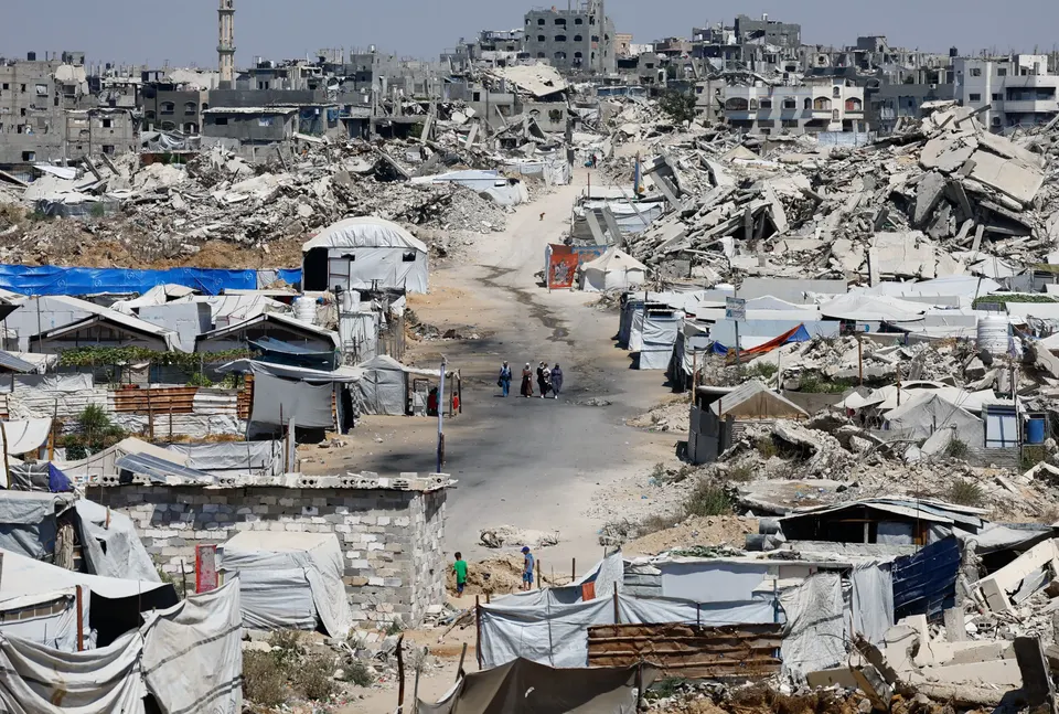People walk at a site destroyed during the Israeli offensive, in Beit Lahiya, in the northern Gaza Strip, August 18, 2026
